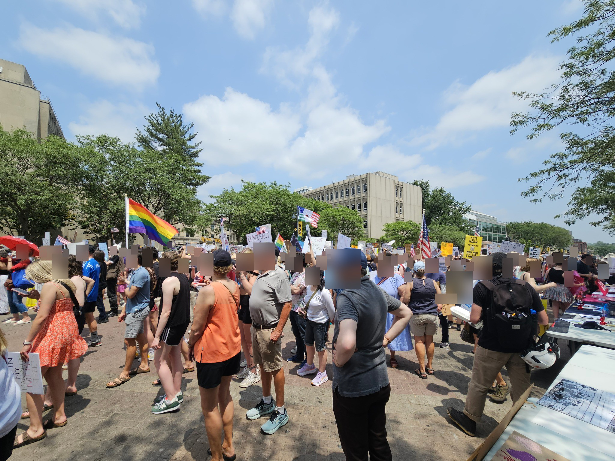 Demonstrators march through downtown Iowa City carrying pride flags, protest signs, and American flags during the No Kings Day rally
