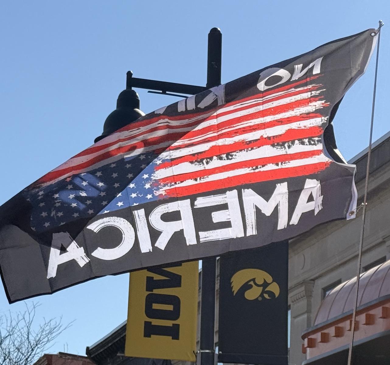 A close-up image of a flag that reads &lsquo;No Kings In America&rsquo; featuring an upside-down US flag design.