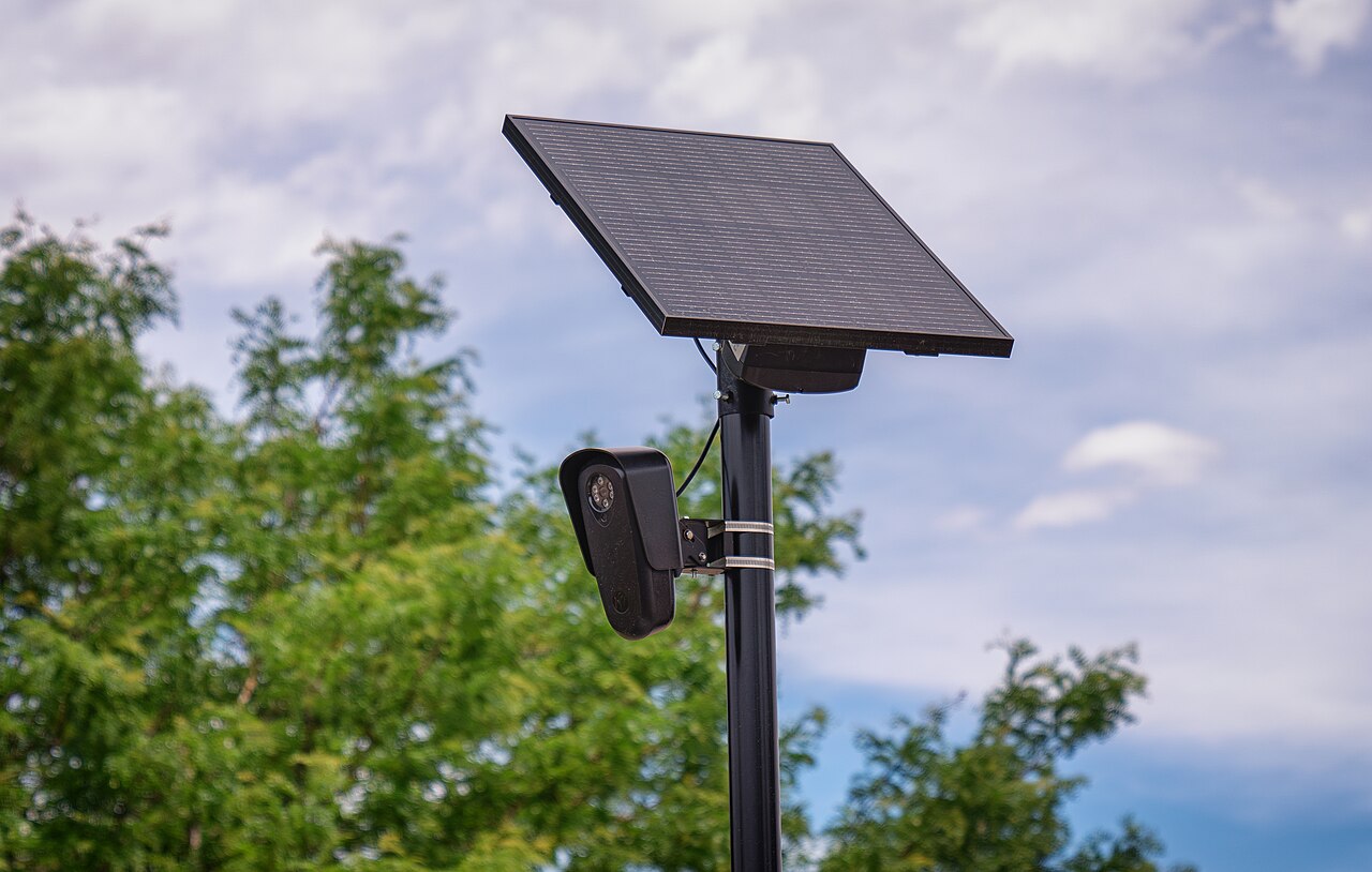 A Flock Safety automated license plate reader camera mounted on a pole outside a retail store