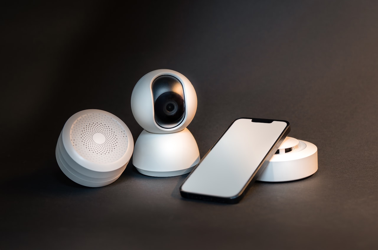A smartphone sitting next to a wireless home security camera